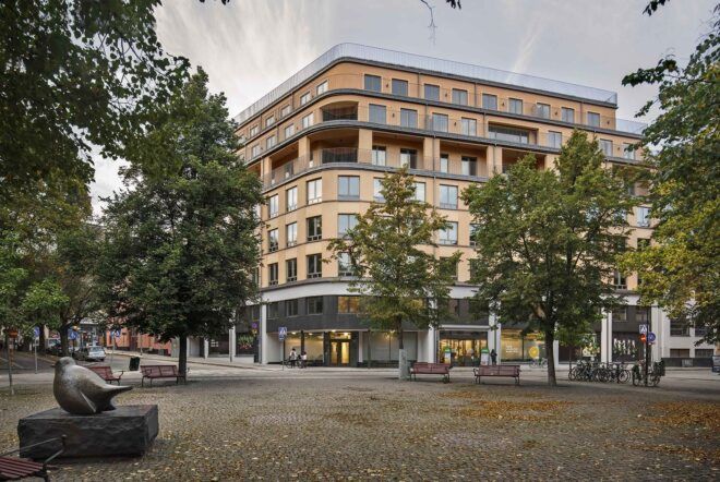 A streetview of an apartment complex with a light brown colored facade and windows.