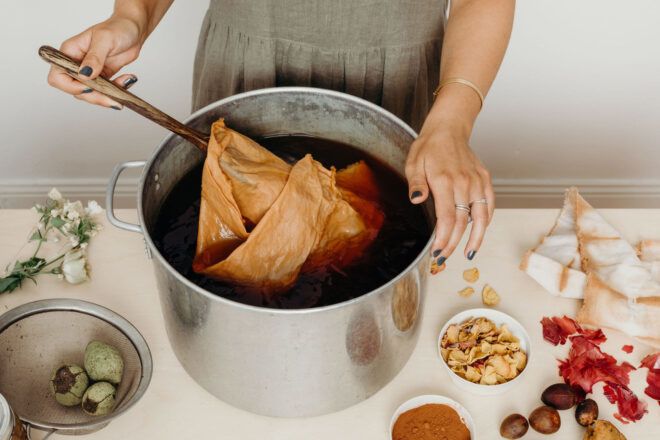 person dyeing fabric in pot of water
