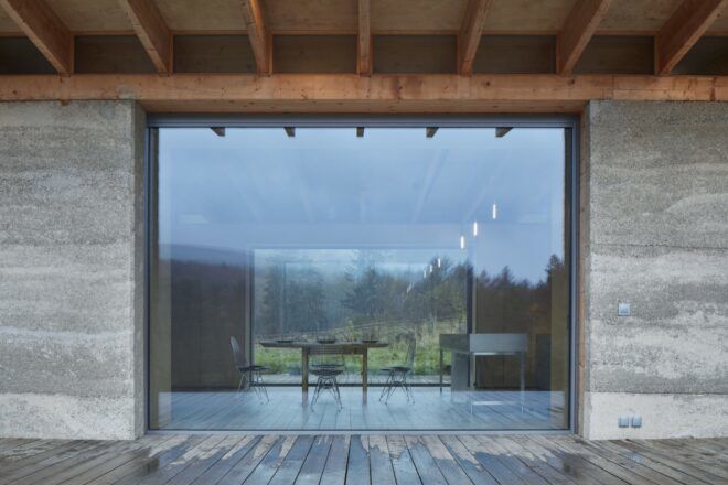 wood patio next to hempcrete home with large glass wall