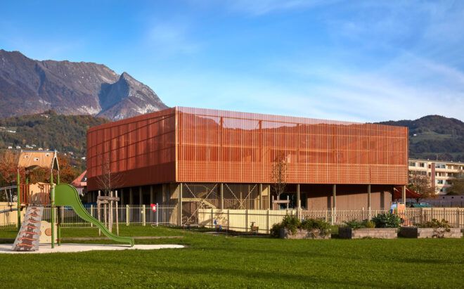 bronze and concrete school building with mountains in the distance