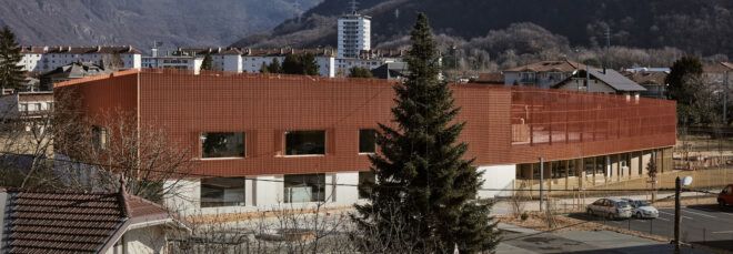 bronze and concrete school building with mountains in the distance