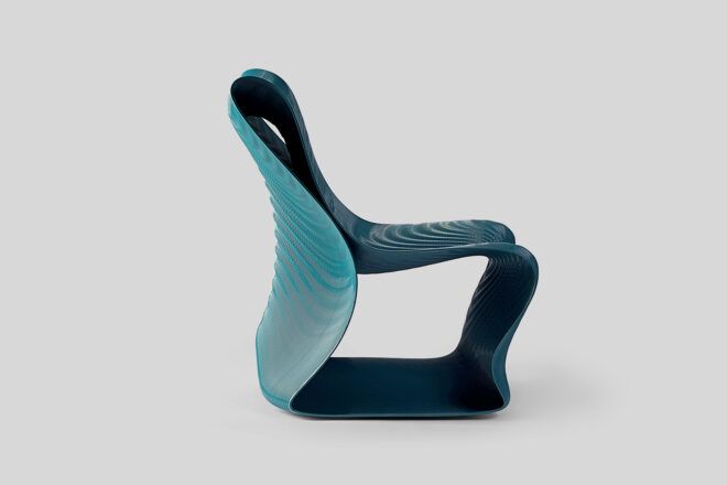 A side view of a dark turquoise 3D-printed chair with a wavy design and texture.