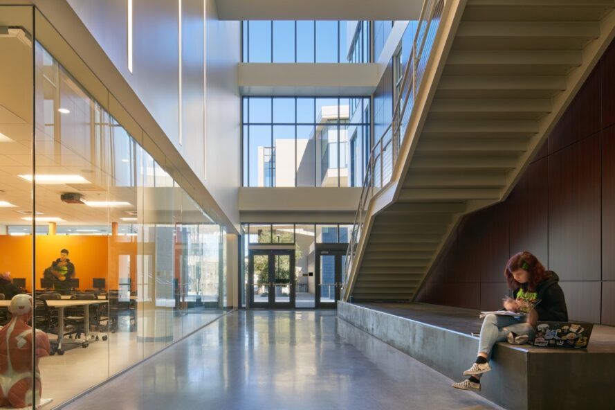 person sitting on bench across from glass-enclosed meeting room