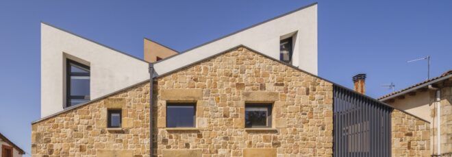 white home barely poking out from behind a stone wall