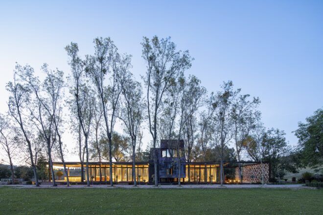 long glass home lit from within at dusk