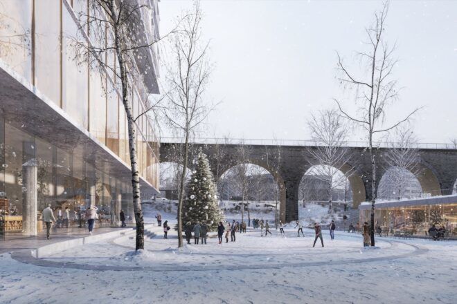 A winter landscape near a building with a connecting bridge with archways for people to walk through.