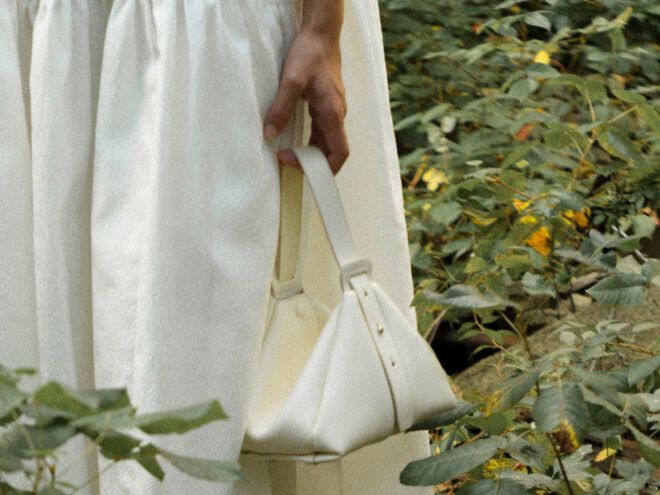 person in white dress carrying white handbag