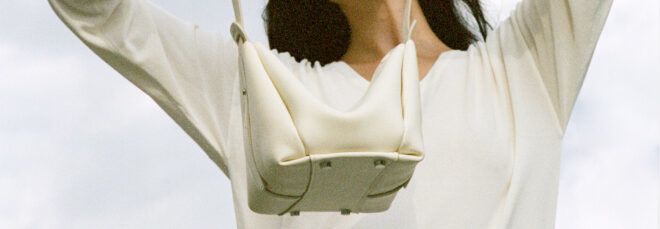 person holding up white leather handbag