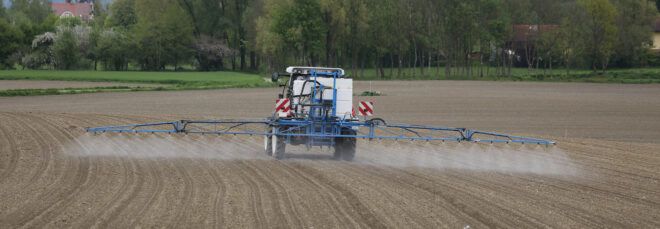 Tractor spraying pesticides on field