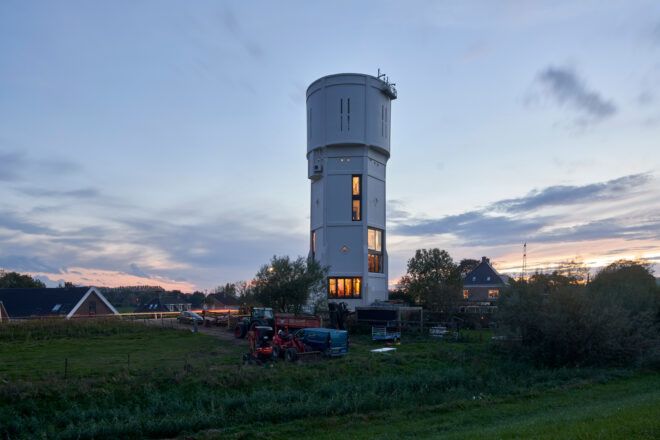 water tower with large windows lit up at dusk