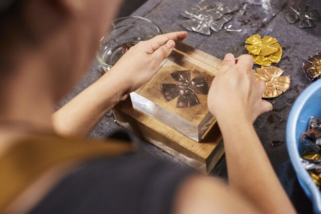 A person holding a translucent box over a flower-like shape in an art studio.