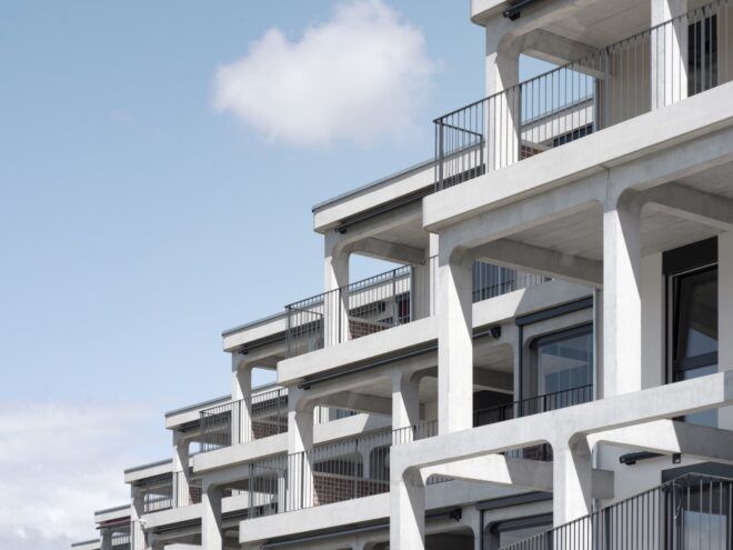 A housing complex with a tiered, off-white facade with balconies.