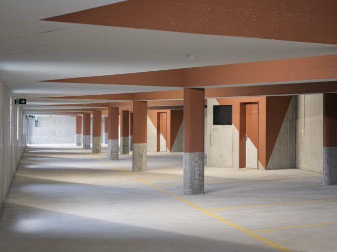A minimalist parking area with orange and white markings on the walls and ceiling.