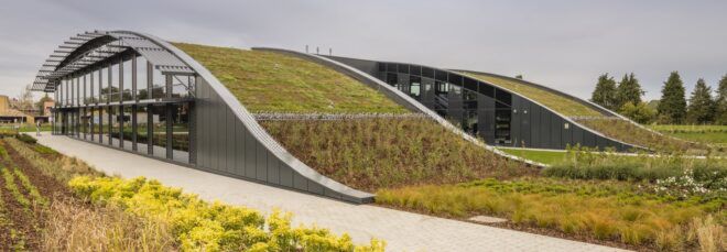 Greenery that connects onto the roof of a curved building with windows on the side.
