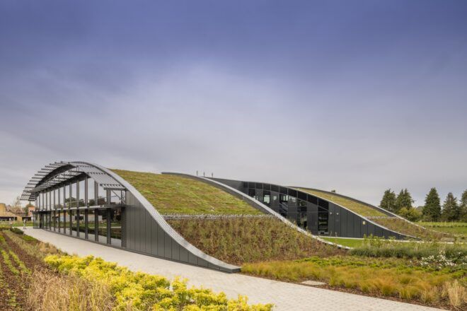 Greenery that connects onto the roof of a curved building with windows on the side.