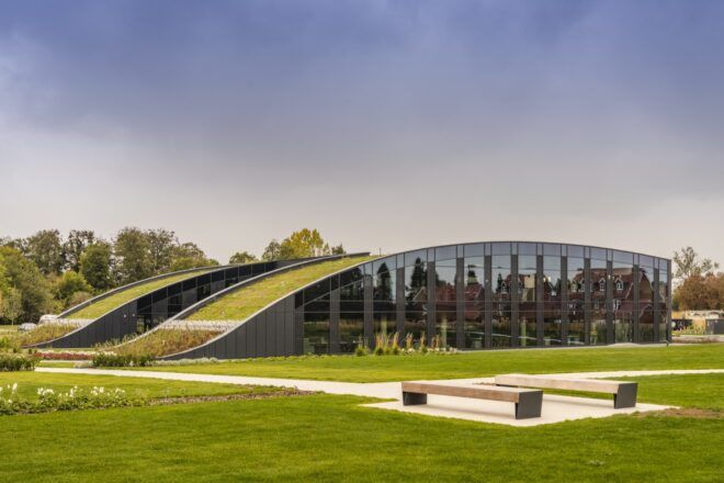 A green lawn surrounding a building with a curved green roof.