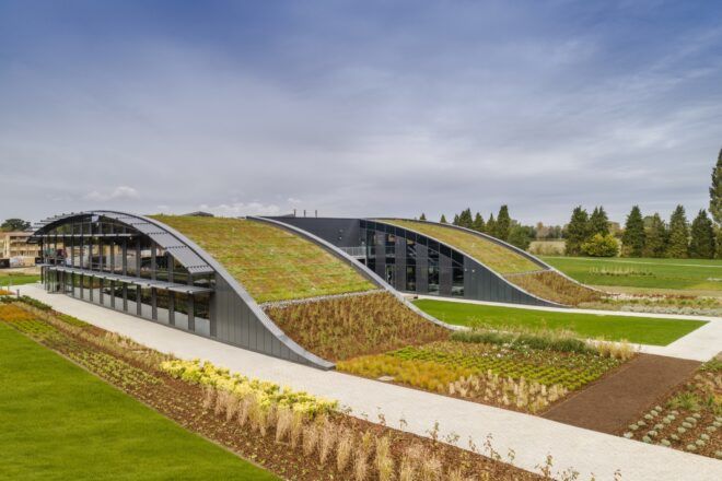 A green lawn surrounding a building with a curved green roof.