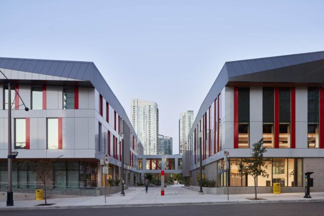 A corridor between two gray buildings with red accents.