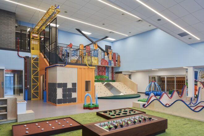 A playroom for kids with several interactive areas, including a toy building crane.