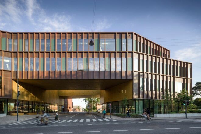glass and copper building with opening for a road to run through it
