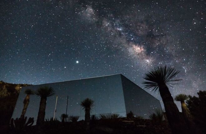 starry night sky above a mirrored cabin