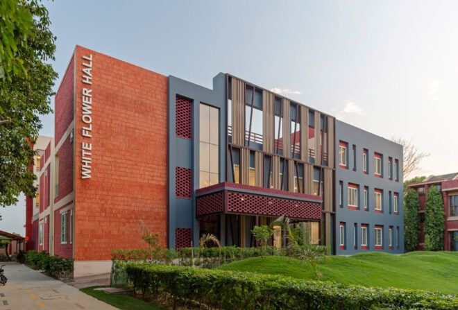 A dorm building with brick, windows and dark blue accents on the facade. The words "White Flower Hall" are written on the side.