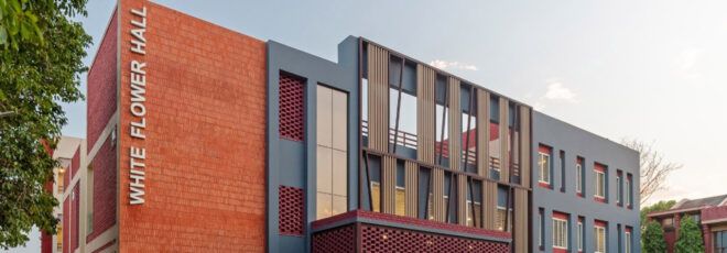 A dorm building with brick, windows and dark blue accents on the facade. The words "White Flower Hall" are written on the side.