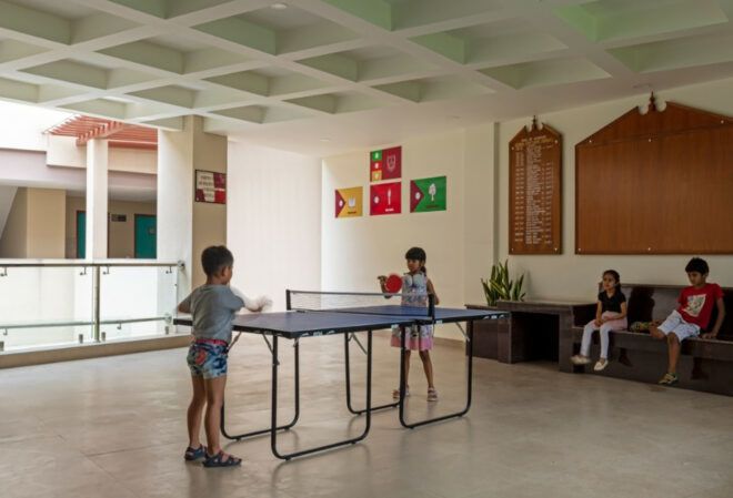 Children playing ping-pong in a game room.