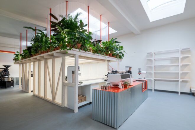 orange and corrugated metal coffee bar with plant-covered loft area above