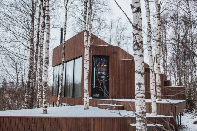 glass and wood cabin in snowy forest