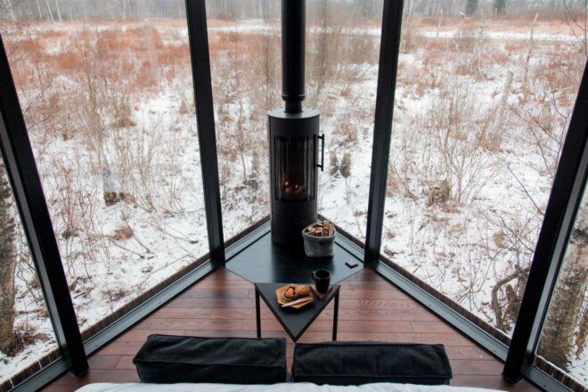 small sofa and table in front of fireplace and two glass walls