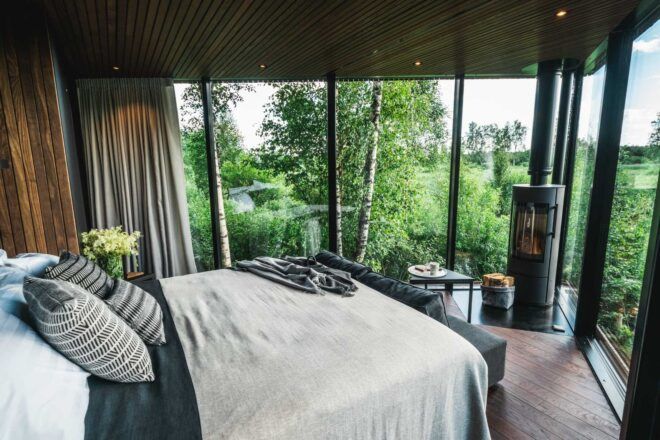 bed facing glass walls with forest views