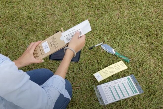 A person on a grassy field using the SoilKit.