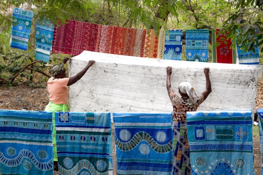 Two people working to hang up large pieces of cloth.