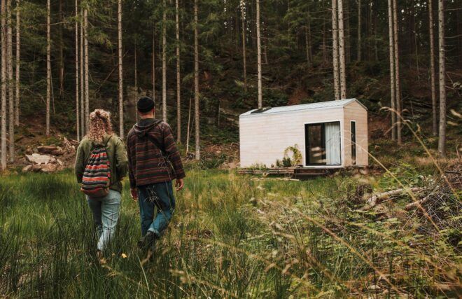 two people walking toward wood tiny home