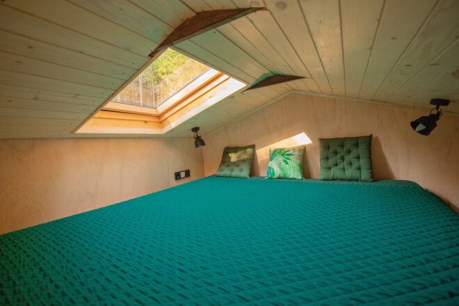 teal bed on a loft under a skylight