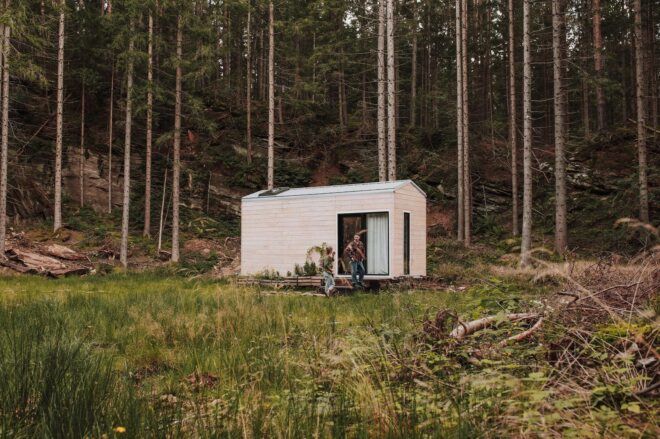 Couple sitting on front porch of wooden tiny home
