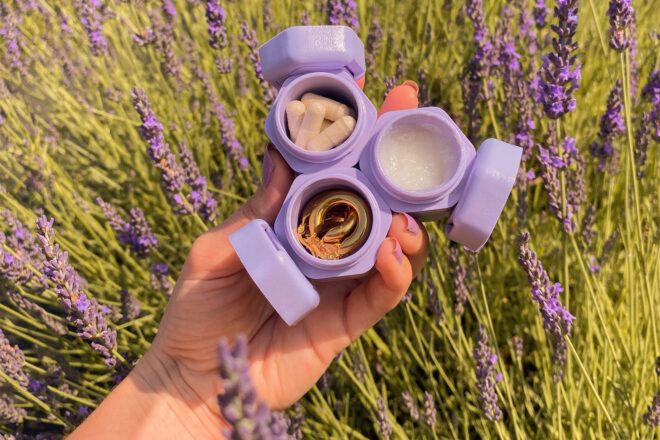 person holding travel capsules up against field of lavender
