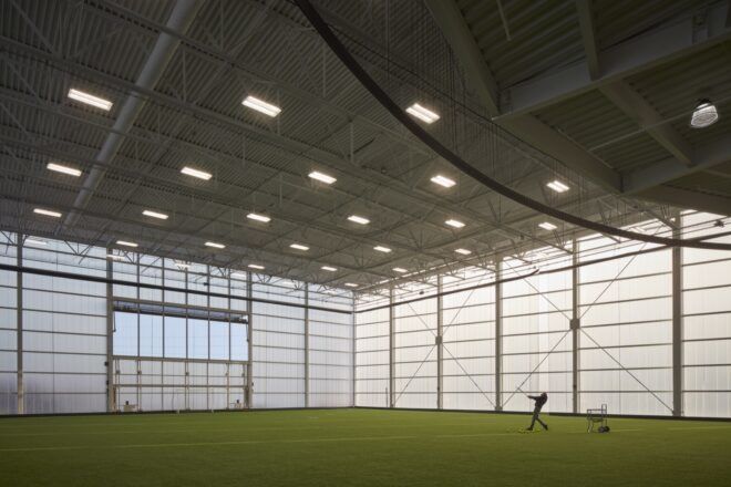 An indoor turf field with a person standing on it.