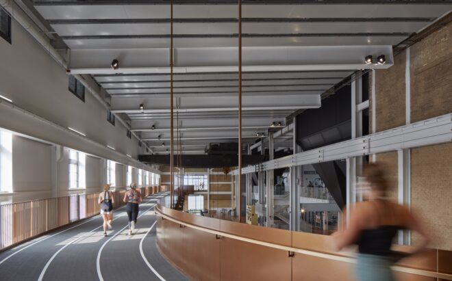 An indoor running track with two people walking on it.