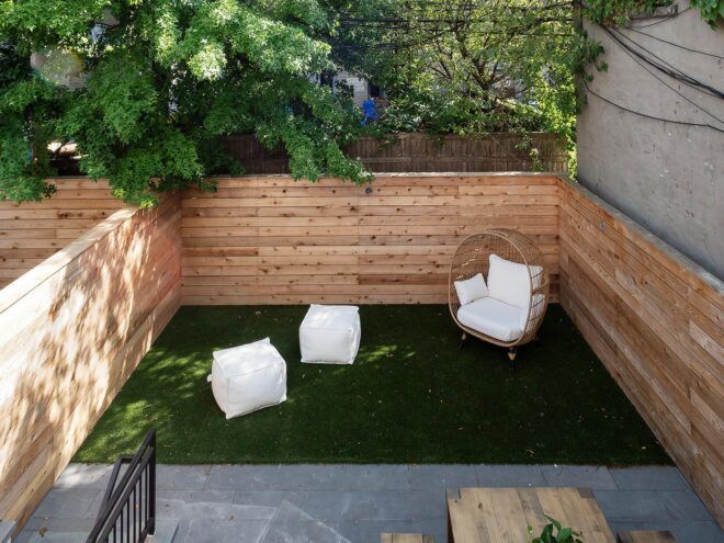 rooftop patio with white chairs surrounded by wood walls