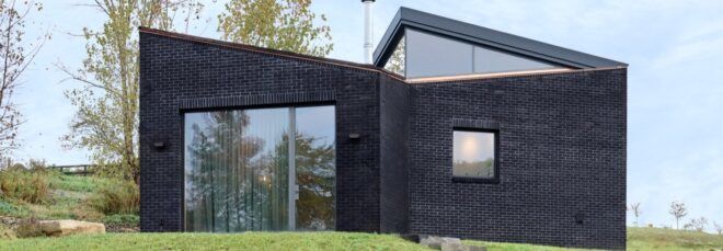 A home with a black brick facade and light-colored wood door.
