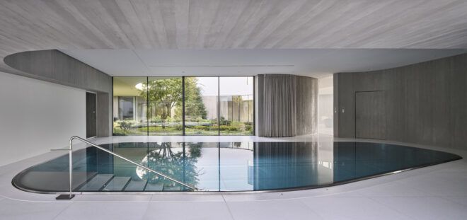 indoor pool in room with glass wall overlooking garden