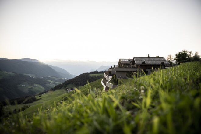 old wood barn on hillside with mountains in the distance