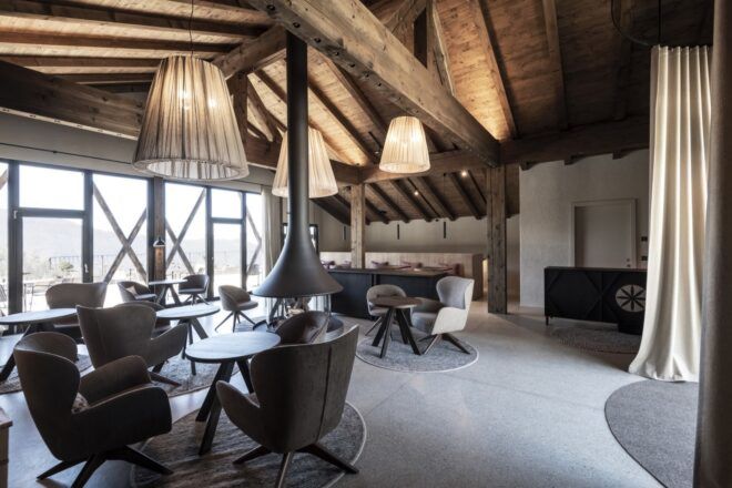 round tables and plush dining chairs in room with exposed wood ceiling