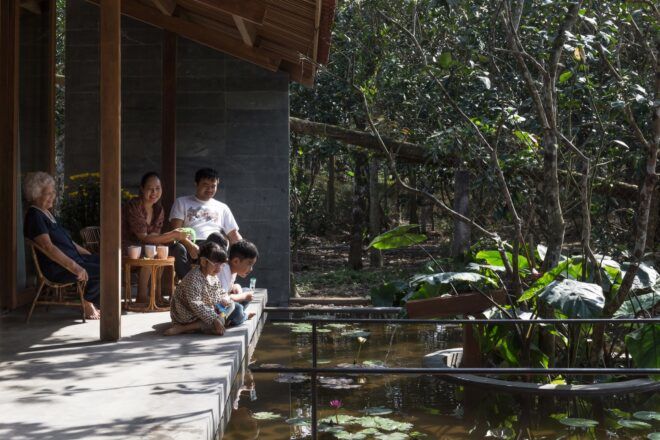 A grandmother, two parents and three children sit on a patio gazing out at the lily pond.