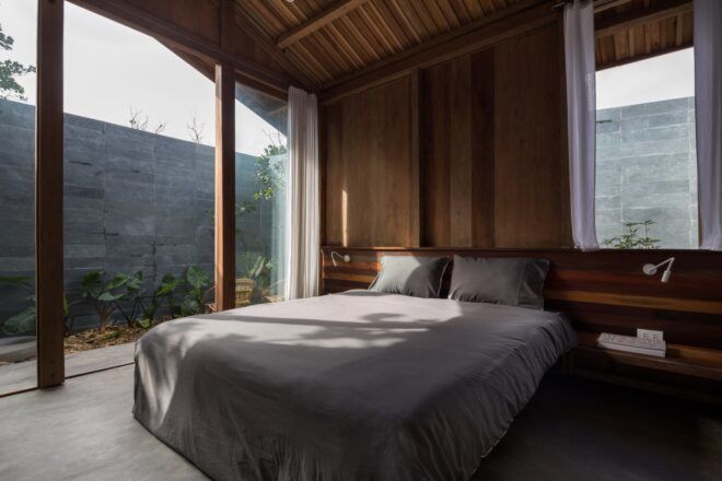A bedroom with a simple white bed. Sliding glass doors connect to a patio area.