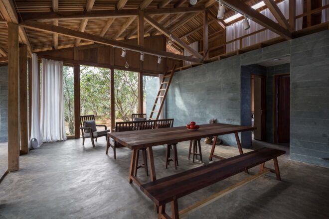 A wooden bench dining table within a plain sitting/dining area.