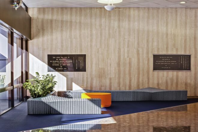A room with wood walls and two blue-gray benches with a round, orange piece of furniture between them.