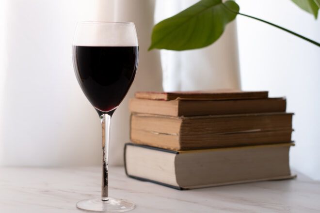 glass of wine by pile of books
